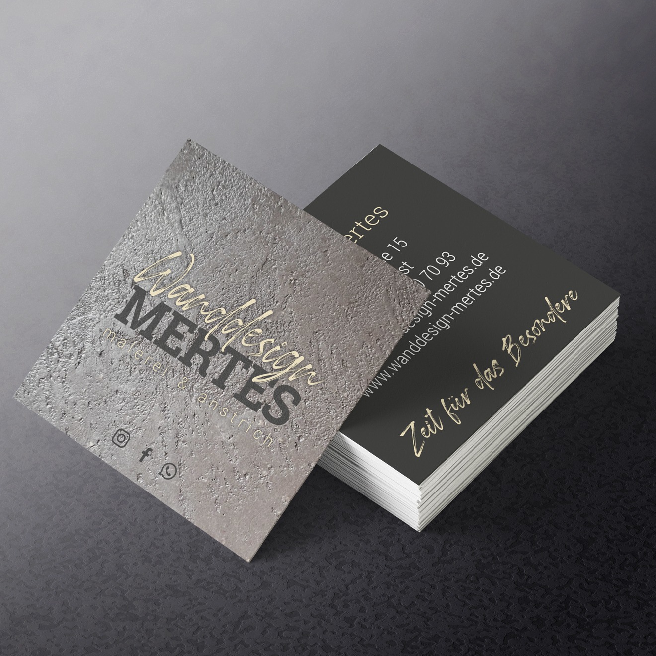 Visitenkarte als Stapel in Steingrauer Wandoptik auf einem dunklen Lederuntergrund.