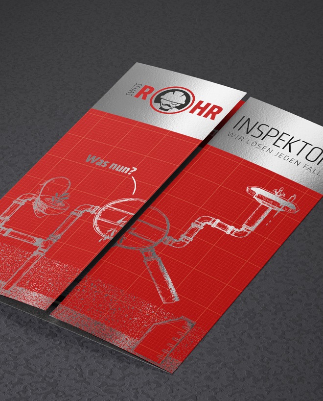 Glaenzender Werbeflyer der Firma swiss Rohrinspektor auf dunkelgrauem Lederuntergrund. In den Hauptfarben Rot/weiß/schwarz und silber. Der Flyer hat einen Chromeffekt und glänzt wie ein Spiegel. Auf der Frontseite des abgebildeteten Flyers ist eine Art technische Zecihn ung zu sehen, die Ein Problem an Rohrleitungen darstellt.